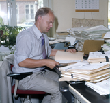 846108 Afbeelding van een medewerker van de provincie Utrecht achter zijn bureau in het provinciehuis aan Achter ...